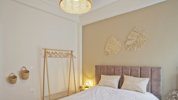 A bedroom with a bed, a wooden drying rack, two wall-mounted baskets, and a wall decor piece. - Pinelopi Spotless 2 BR Renovated Apt Athens Center (Athens)