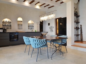 A modern kitchen with built-in appliances, a dining area with tufted chairs, and a chandelier. - Waterside Cove Oasis Apartment Rovinj (Rovinj)