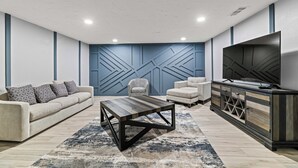A modern living room with a sofa, armchair, coffee table, and entertainment unit. - Sunset Heights Retreat- 3 Stylish & Spacious Bedroom (Fort Worth)