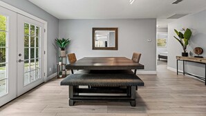 A dining area with a large table, bench, and potted plants. - Sunset Heights Retreat- 3 Stylish & Spacious Bedroom (Fort Worth)