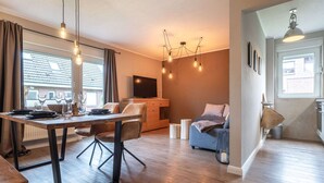 A modern living room with a dining area, a television, and a sofa. - Apartment in Busum Near Perlebucht Lagoon (Westerdeichstrich)
