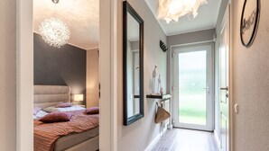 Un dormitorio con cama, lámpara de noche y lámpara colgante.
