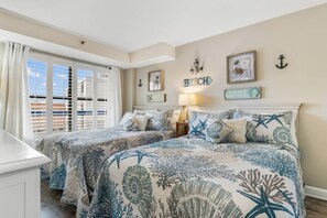 A bedroom with two beds, a window with blinds, and a wall with nautical-themed decor. - Luxury Ocean View Condo- Relaxing Exclusive Access (Myrtle Beach)