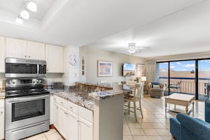 A modern kitchen with built-in appliances, a dining area with a view, and a balcony with outdoor seating.