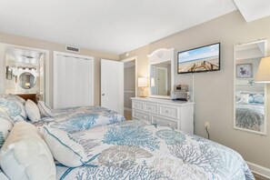 A bedroom with two beds, a dresser, a mirror, and a television. - Luxury Ocean View Condo- Relaxing Exclusive Access (Myrtle Beach)
