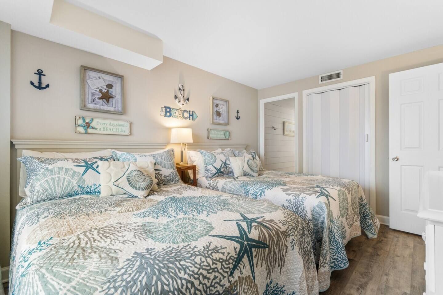 A bedroom with two beds, a nightstand, and a wall with nautical-themed decorations.
