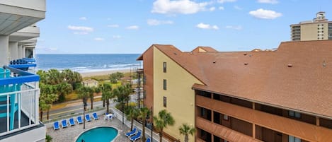 A hotel with a pool area, a view of the beach, and a multi-story building.