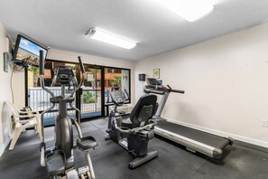 A gym with cardio machines, a treadmill, and a bench.