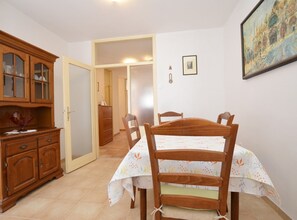 A room with a wooden dining table, chairs, a cabinet with glass doors, and a door leading to another room. - Airy and Comfortable Apartment With Loggia (Rovinj)