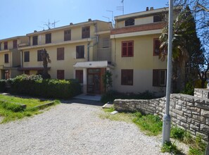 A multi-story building with a gravel driveway leading to a gated entrance. - Airy and Comfortable Apartment With Loggia (Rovinj)