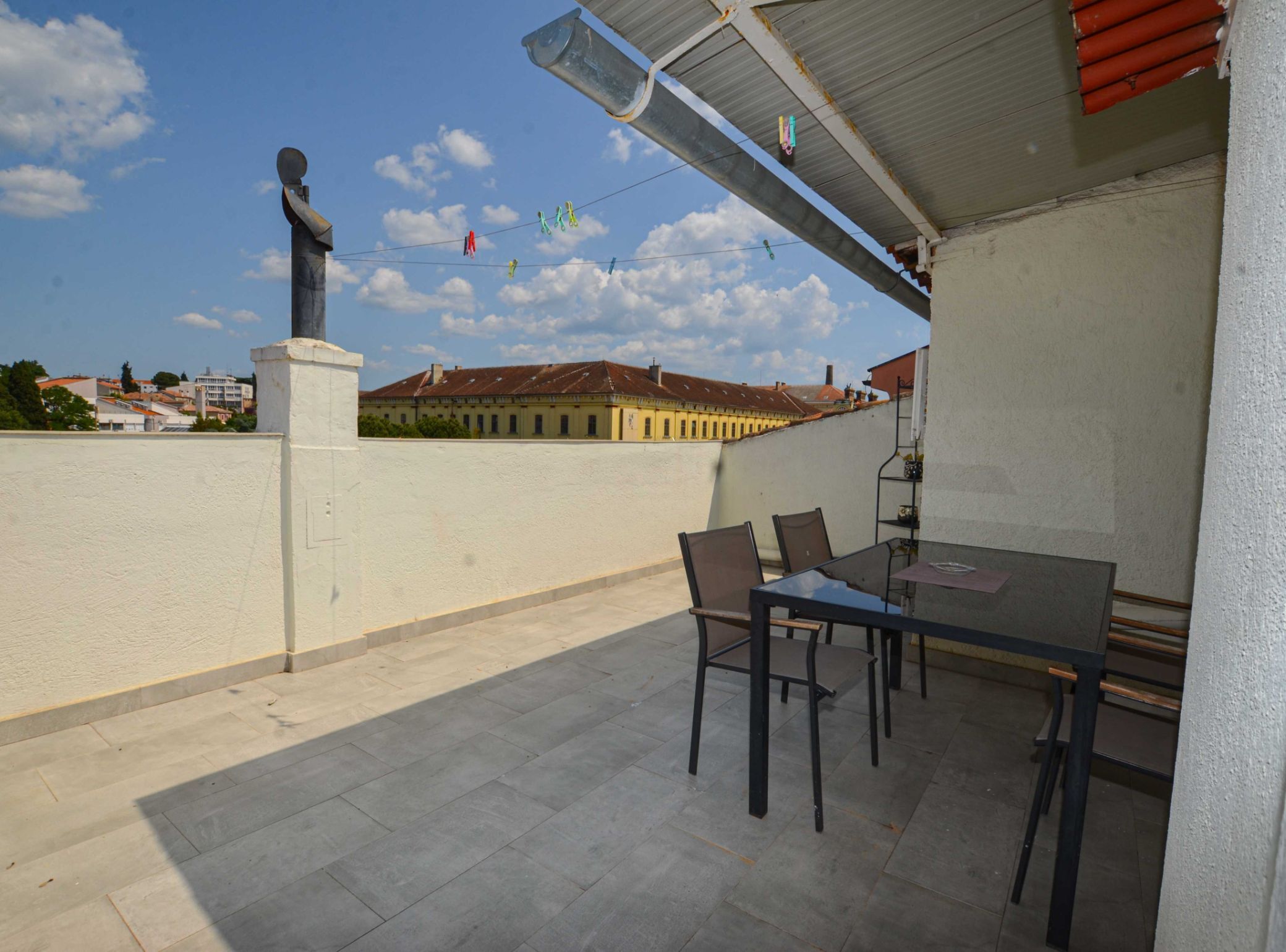 An outdoor patio with a table and chairs, a statue, and a view of buildings in the background.