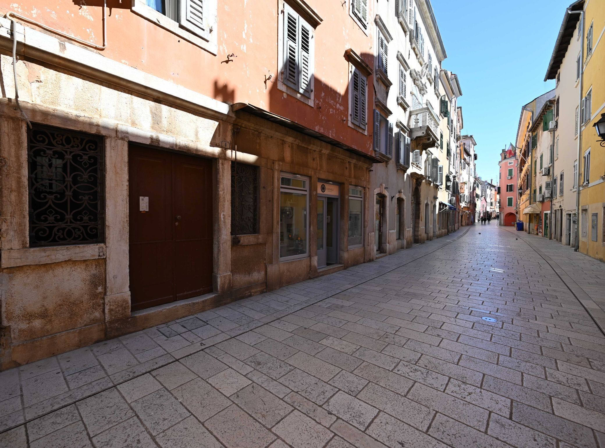 A narrow street lined with historic buildings, featuring a cobblestone pavement and traditional architecture.