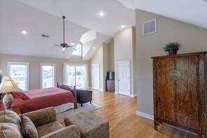 A spacious bedroom with a large bed, a ceiling fan, and a view of the outdoors.