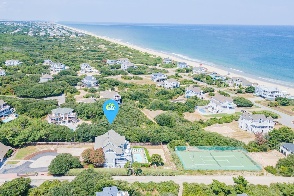Ein Luftbild eines Küstenwohngebiets mit Häusern, einem Strand und einem Tennisplatz.