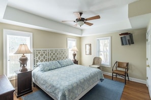A bedroom with a bed, two lamps, a chair, a ceiling fan, and a window. - Sun Realty gorgeous oceanside retreat with an elevator in Corolla NC! (Corolla)