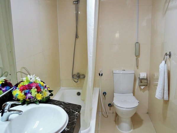 A bathroom with a white sink, a toilet, a shower, and a mirror. - Palette - Top Stars Hotel (Abu Dhabi)