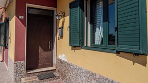 A building with a stone base, a wooden door, and green shutters. - Sophie (Cellino San Marco)