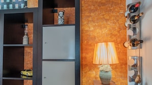 A room with a wooden cabinet, a lamp, and a wall-mounted wine rack. - Sophie (Cellino San Marco)