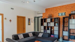 A modern living room with a sectional sofa, a coffee table, and built-in bookshelves. - Sophie (Cellino San Marco)