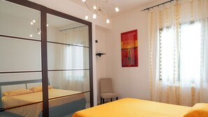 A hotel room with a bed, a chair, a window with curtains, and a painting on the wall. - Sophie (Cellino San Marco)
