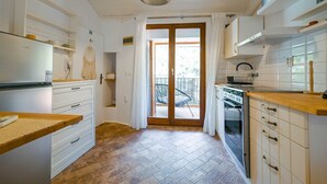 A modern kitchen with white cabinets, a built-in oven, and a wooden countertop. - Snug and Stylish Downtown Rovinj Apartment (Rovinj)