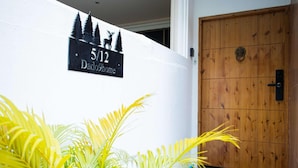 A house number sign, a wooden door, and a doormat. - Dado9 (Bangkok)
