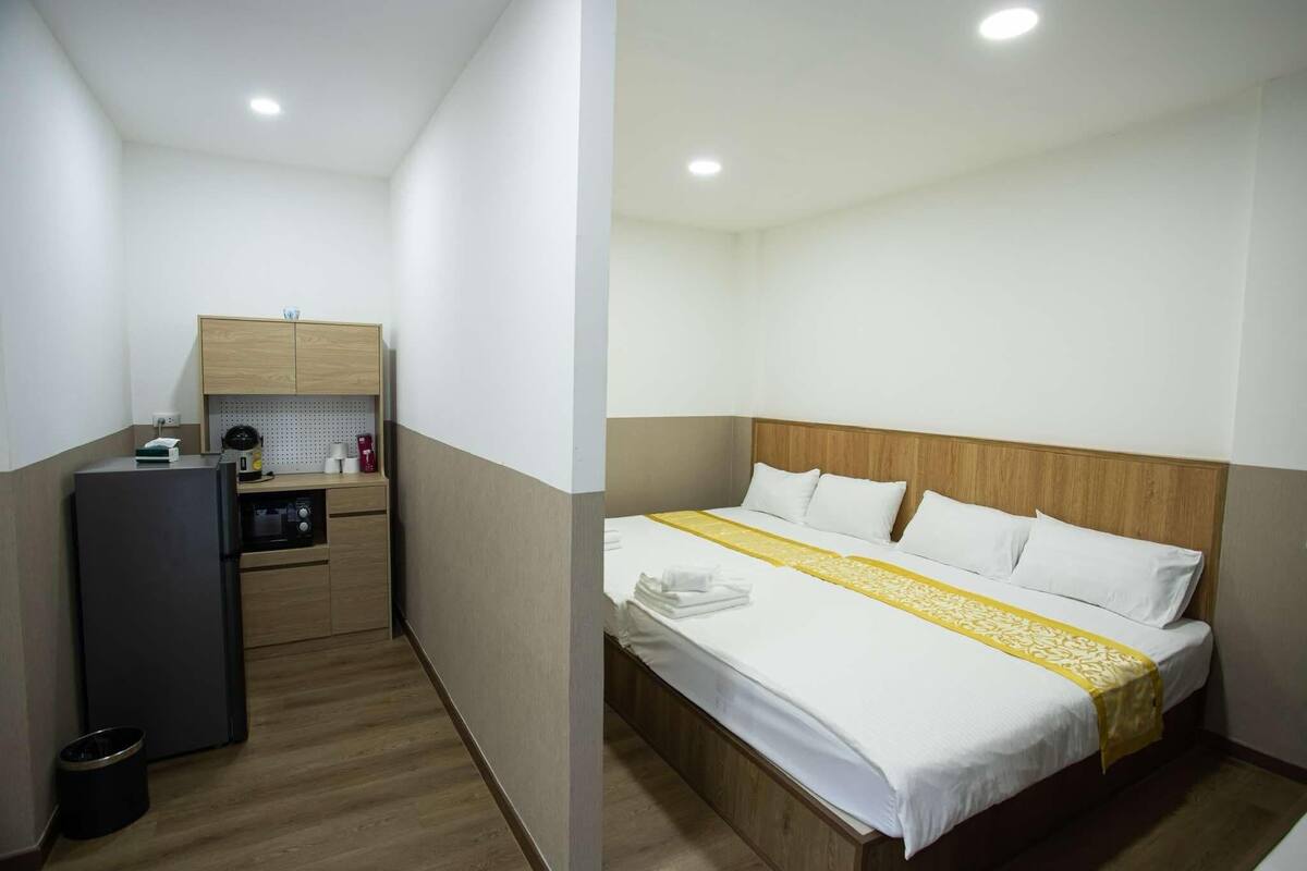 A hotel room with a bed, a small kitchenette, and a wooden headboard.