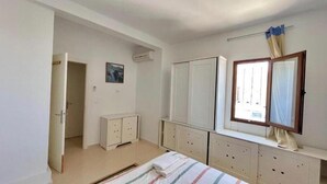 A bedroom with a bed, a wardrobe, a dresser, and a window with curtains. - Sweet Villa Residence (Houmt Souk)
