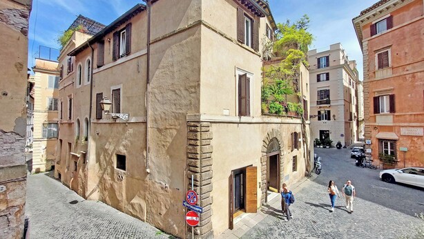 Una estrecha calle adoquinada con edificios históricos, una señal de no estacionamiento y peatones.