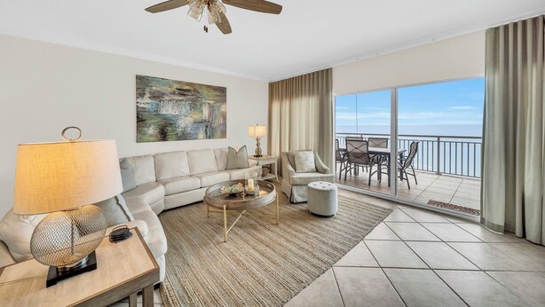 A modern living room with a sofa, coffee table, and a balcony with a view. - Admirals Quarter 908, 3 bedroom, 3 bath coastal oasis (Orange Beach)