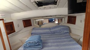 Une petite cabine bien aménagée et bien éclairée, avec un lit, une petite table et une fenêtre laissant entrer la lumière naturelle.