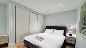 A bedroom with a bed, nightstands, a lamp, a wardrobe, and a window with blinds. - London Charm - Central London Apart Soho Mayfair (London)