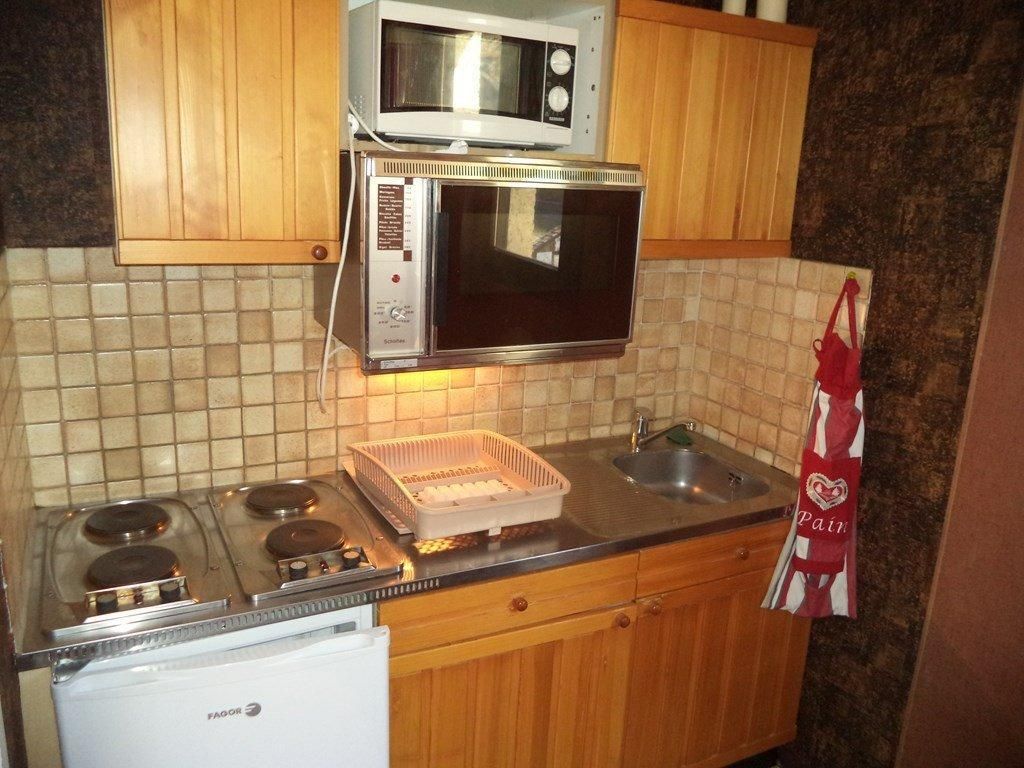 Una cucina con fornello, forno a microonde e forno. C'è un lavello e un pensile sopra il fornello.