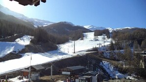 Un centro de esquí con telesilla, un edificio pequeño y una montaña cubierta de nieve al fondo.