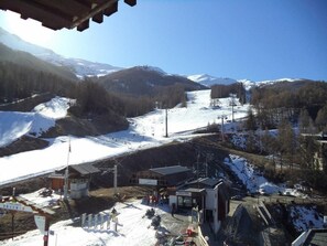A ski resort with a chairlift, a small building, and a snow-covered mountain in the background.