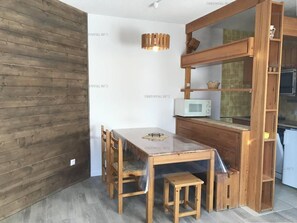 Une cuisine de taille réduite, avec une table en bois, des chaises, un four à micro-ondes et un meuble en bois.