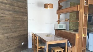 A compact kitchen with a wooden table, chairs, a microwave, and a wooden cabinet. - 40m from shops, 4th floor, balcony, tv, 30m², Les Orres (Les Orres)