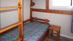 A bunk bed with a small table beside it, a window with a curtain, and a plain wall. - 40m from shops, 4th floor, balcony, tv, 30m², Les Orres (Les Orres)