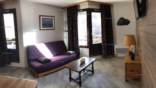 A living room with a purple sofa, a wooden coffee table, and a small wooden side table with a lamp. - 40m from shops, 4th floor, balcony, tv, 30m², Les Orres (Les Orres)