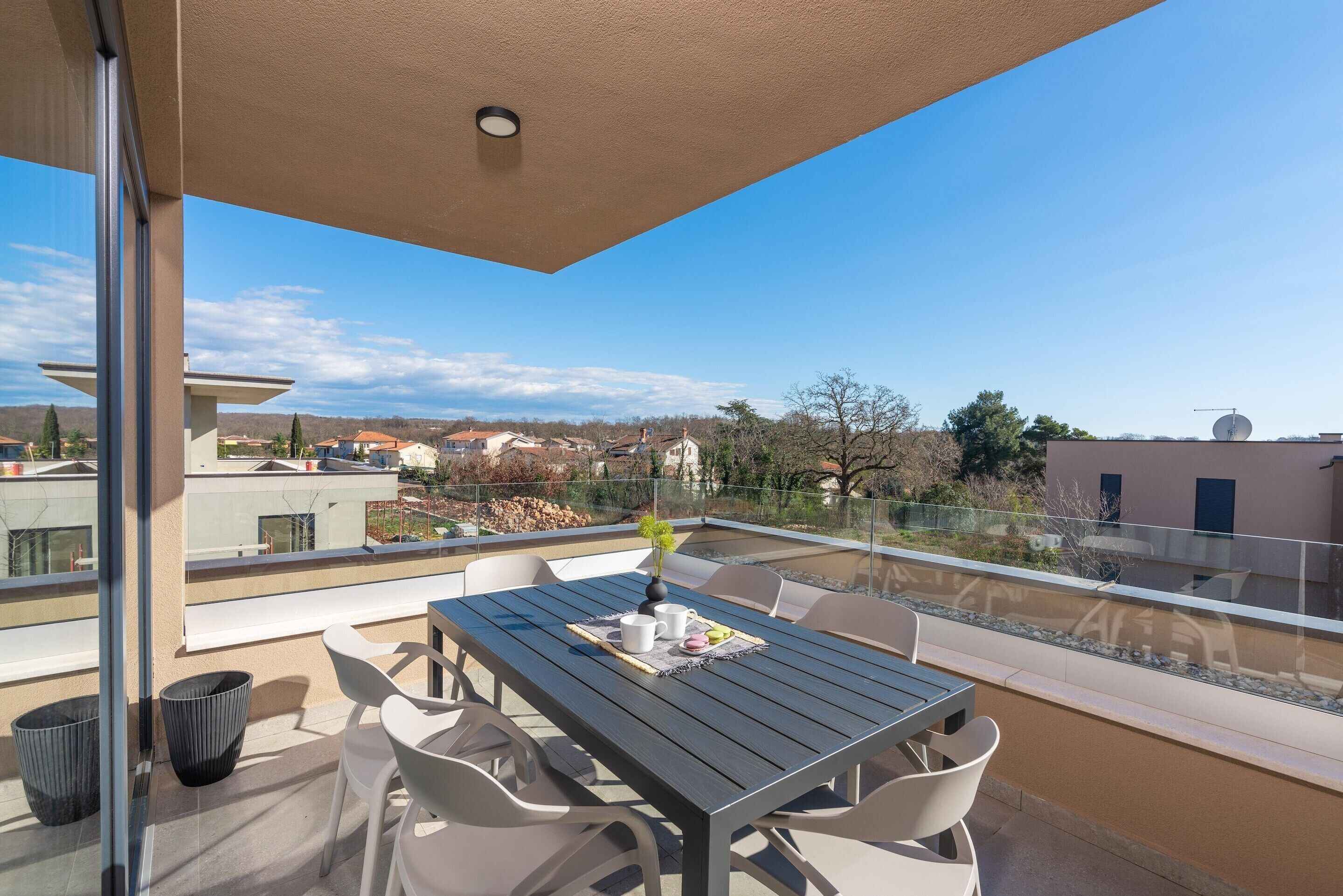 Ein Balkon mit Tisch und Stühlen, einer Blumenvase und freiem Blick auf die Umgebung.