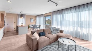 A modern living room with a sofa, a coffee table, and a dining area with a table and chairs. - Apartment in Pula With Sea View and Bubble Bath (Brtonigla)