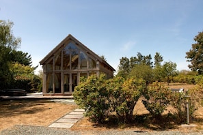 A modern building with a triangular roof and large windows, surrounded by a gravel path and greenery. - Peaceful Nature Retreat in Othery (Bridgwater)