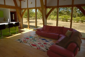 A spacious room with a red sofa, a patterned rug, and a view of the outdoors through large windows.