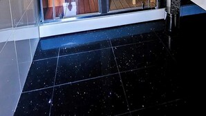 Ein modernes Badezimmer mit einer Glastür, die zu einem Holz-Saunabereich führt.