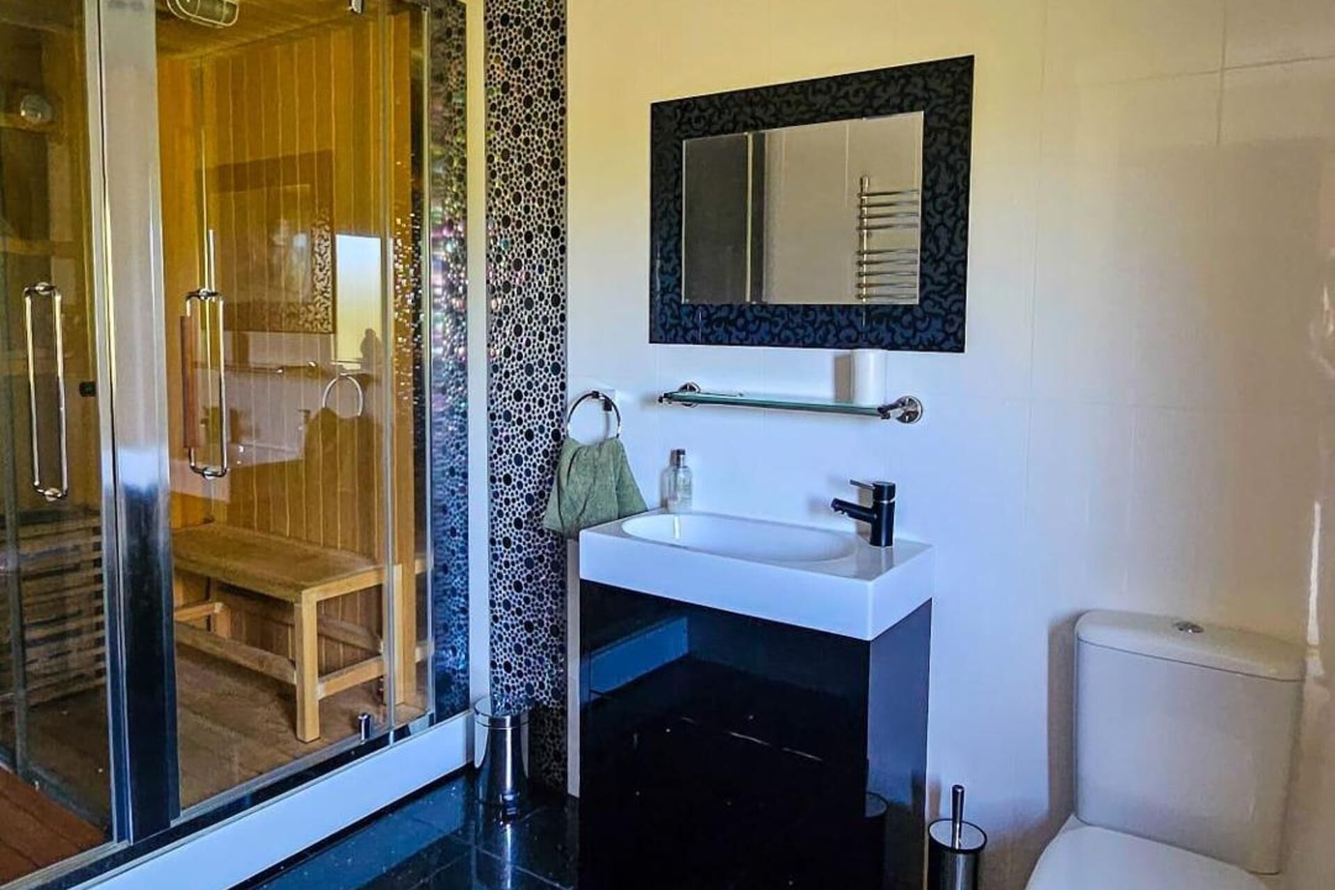 Un baño moderno con cabina de ducha de vidrio, un lavamanos blanco y un inodoro.