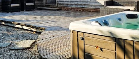 Eine Holzterrasse mit Whirlpool, einer Ziegelpatio und einer kleinen Sitzgruppe im Freien.