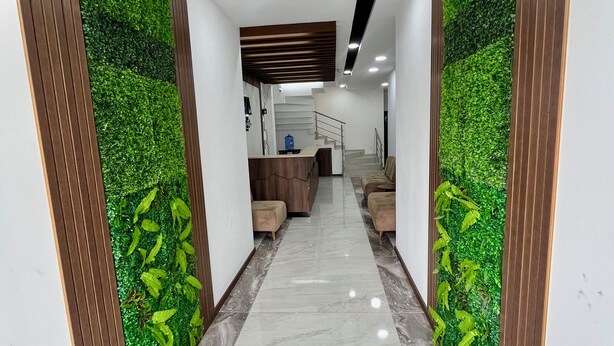 A modern hallway with a marble floor, wooden paneling, and green artificial foliage on the walls. - Hotel RYA Center (Ibarra)
