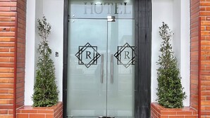 A hotel entrance with a glass door, a sign reading "HOTEL", and two potted plants on either side. - Hotel RYA Center (Ibarra)