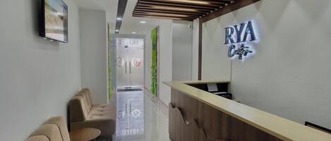 A modern reception area with a wooden reception desk, a sofa, and a wall-mounted sign that reads "RYA Center".