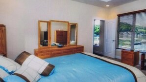 Una habitación de hotel moderna con una piscina grande, un ventilador de techo y un ventanal con persianas.